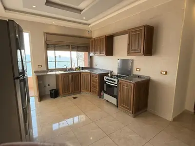 a kitchen with wooden cabinets and a stove top oven at شقه للإيجار عجلون -رأس منيف in Ajloun