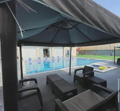 a large blue umbrella next to a swimming pool at Qubaisi chalet in Al Rama