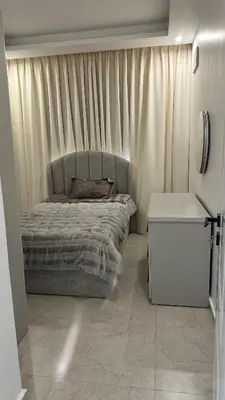 a bedroom with a bed and a table and curtains at Furnished Apartment in Bushrá