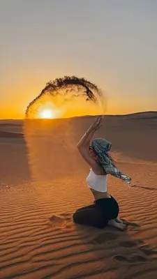 a woman sitting on the sand in the desert at Wadi rum magic Luxury in Wadi Rum