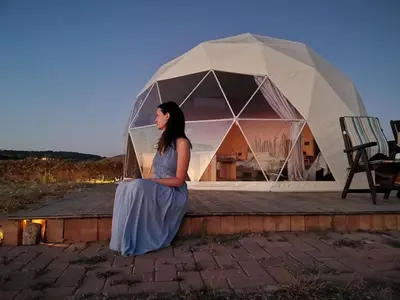 a woman sitting on a wall in front of a tent at Wadi rum magic Luxury in Wadi Rum