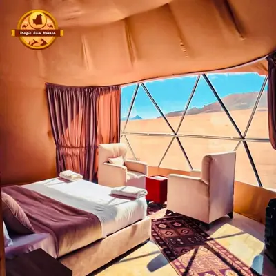 a bedroom with a bed and two chairs and a large window at Wadi rum magic Luxury in Wadi Rum
