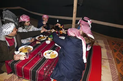 a group of people sitting around a table eating food at Hillawi Private Bedouin Camp in Wadi Rum