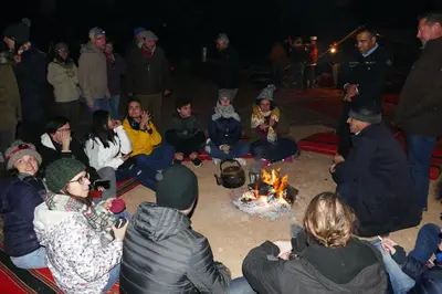 a group of people sitting around a fire at Hillawi Private Bedouin Camp in Wadi Rum