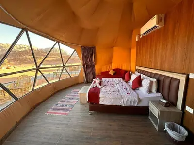 a bedroom with a bed in a room with large windows at Echo of the Sands in Wadi Rum