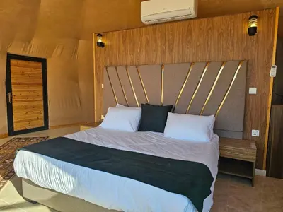 a bedroom with a large bed with a wooden headboard at Echo of the Sands in Wadi Rum