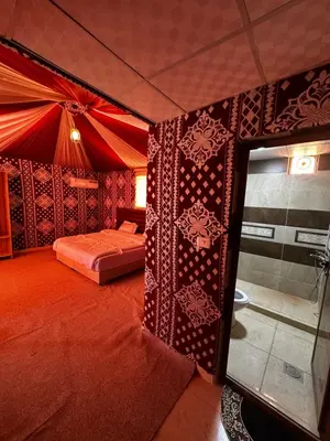 a red room with a bed and a shower at Desert Star Camp in Disah