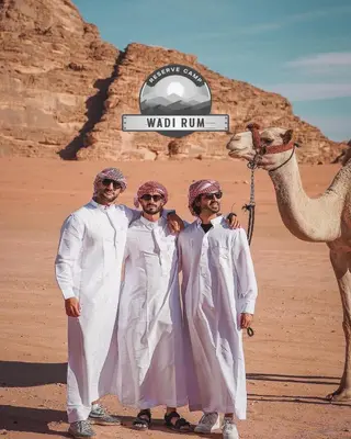 three men standing next to a camel in the desert at WADI RUM RESERVE BUBBlE CAMP in Wadi Rum
