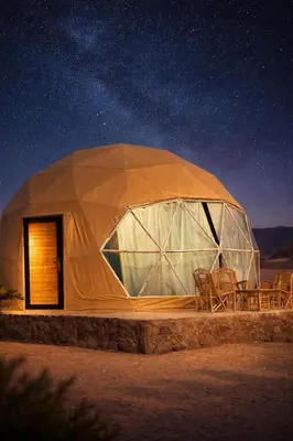 a dome tent with chairs in the desert at night at Ram Camp Desert in Wadi Rum