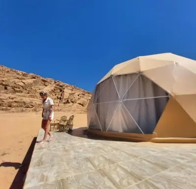 a man standing next to a tent on the beach at Ram Camp Desert in Wadi Rum