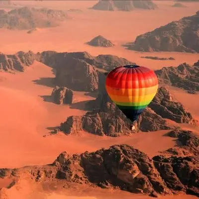 a hot air balloon flying over a mountain at Ram Camp Desert in Wadi Rum