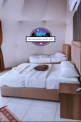 two beds in a room with a sign on the wall at RUM LARA BUBBLES lUXURY CAMP in Wadi Rum