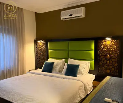 a bedroom with a large bed with a green headboard at Ajaza Real Estate in Amman
