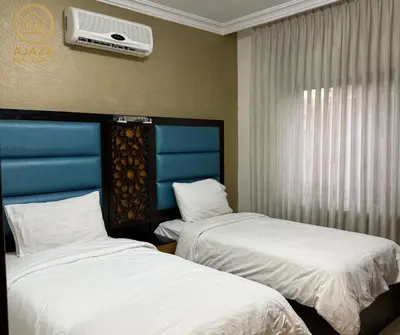 a room with two beds and a air conditioner on the wall at Ajaza Real Estate in Amman