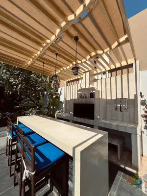 an outdoor kitchen with a table and a grill at Mirabella Villa in Al Rama