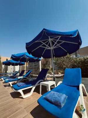 a row of blue and white chairs and umbrellas at Mirabella Villa in Al Rama