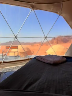 a bed in a tent with a view of the desert at Luxury Camp Wadi Rum in Disah