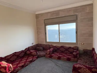 a living room with a couch and a window at شقة للإيجار في عجلون in Ajloun