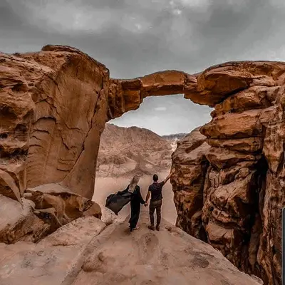 two people walking through an arch in the desert at Solar Soul Camp - Wadi Rum Desert Experience & Stargazing in Wadi Rum