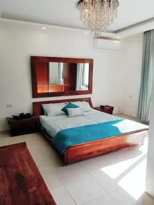 a bedroom with a large wooden bed with a chandelier at Luxury 3 bedrooms flat with great view of Amman in Amman