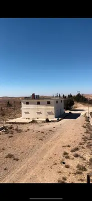 a building in the middle of a desert with a dirt road at البترا Petra in Abū al Lasan