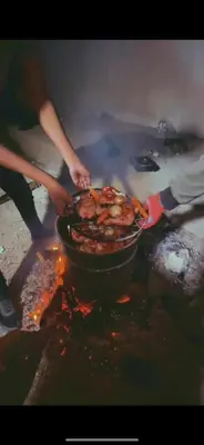 a person cooking food in a pot on a fire at البترا Petra in Abū al Lasan