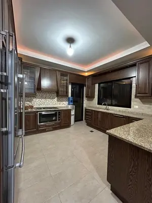 a large kitchen with wooden cabinets and a refrigerator at 3BR Escape with Outdoor Scenic Views in Amman