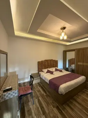 a bedroom with a large bed and a desk and a ceiling at 2bedrooms sport city in Amman