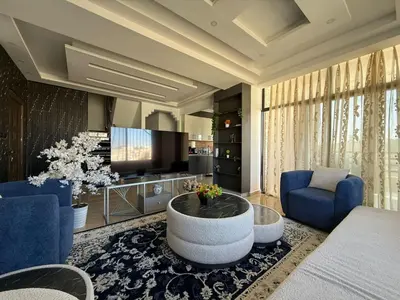 a living room with blue chairs and a coffee table at 2bedrooms sport city in Amman