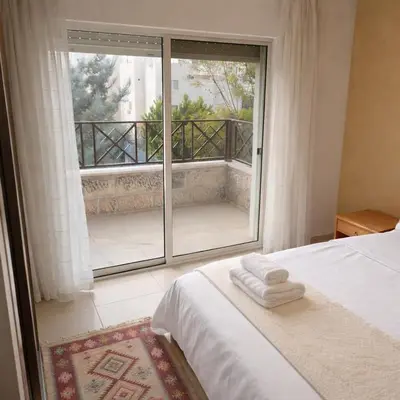 a bedroom with a bed and a large window at Mecca Street Cozy Apartment in Amman