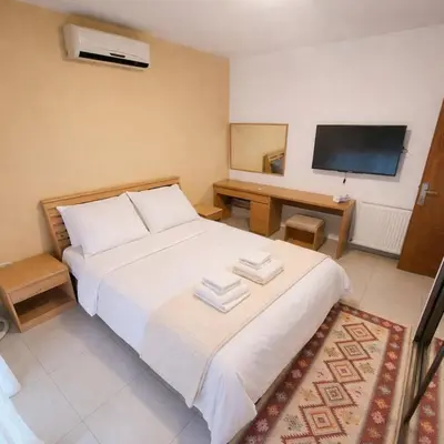 a bedroom with a white bed and a flat screen tv at Mecca Street Cozy Apartment in Amman