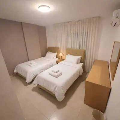 two beds in a small room with white sheets at Mecca Street Cozy Apartment in Amman