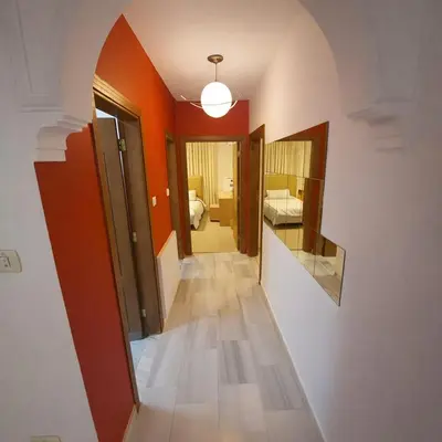 a hallway with a mirror and a room with a bed at Mecca Street Cozy Apartment in Amman