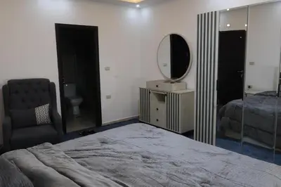 a bedroom with a bed and a mirror and a chair at شقق الاستقلال in Amman