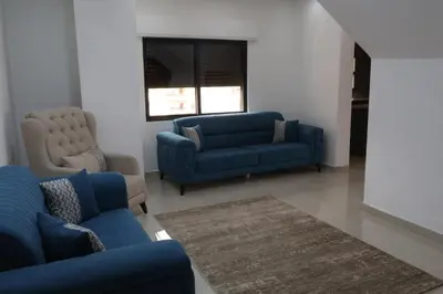 a living room with two blue couches and a window at شقق الاستقلال in Amman