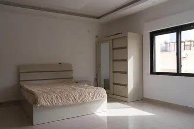 a white bedroom with a bed and a window at شقق الاستقلال in Amman