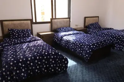 three beds in a room with blue comforters at شقق الاستقلال in Amman
