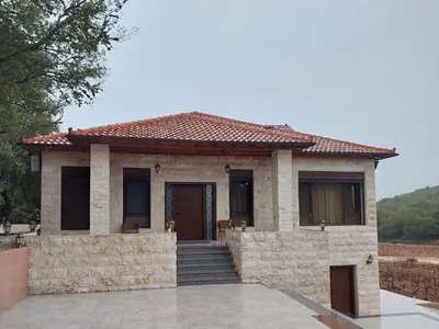 a small house with a stone wall and stairs at Bait Ajloun in Khirbat Shīn