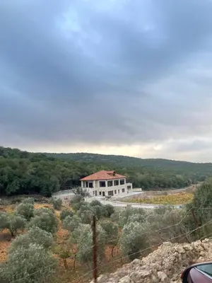 a large white house on the side of a road at Bait Ajloun in Khirbat Shīn