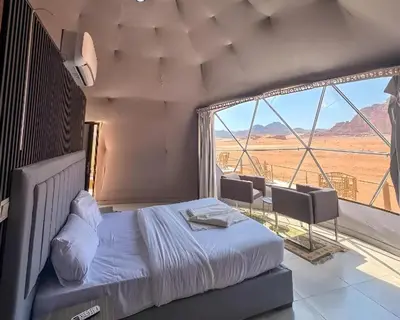 a bedroom with a bed and a large window at Teraa rum luxury camp in Wadi Rum