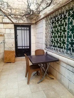 a table and chairs in a patio with a window at Flowers in Jerash