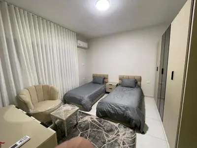 a small room with two beds and a chair at apartement khaled in Madaba