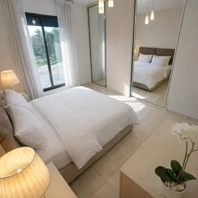 a bedroom with a large white bed and a mirror at Abdoun Elite Residence Stunning View in Amman