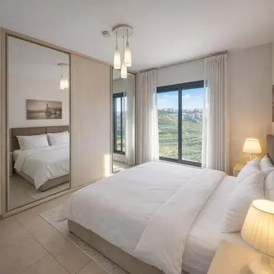 a bedroom with a large white bed and a large mirror at Abdoun Elite Residence Stunning View in Amman