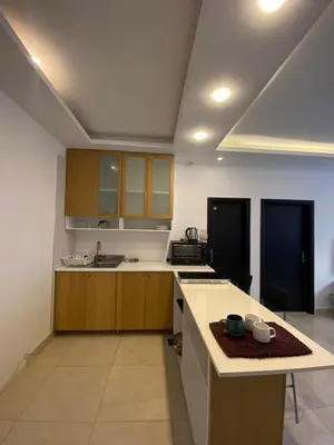 a kitchen with wooden cabinets and a counter top at Cozy Wabida in Amman