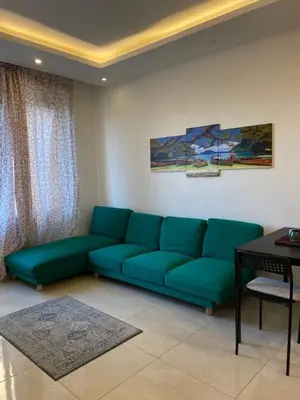 a living room with a green couch and a table at Cozy Wabida in Amman