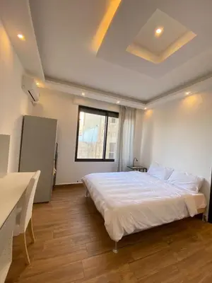 a bedroom with a bed and a table and a window at Cozy Wabida in Amman
