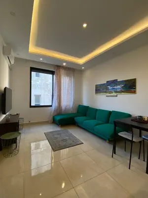 a living room with a green couch and a table at Cozy Wabida in Amman
