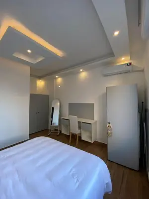 a bedroom with a large white bed and a desk at Cozy Wabida in Amman