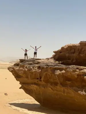 two people standing on a rock on the beach at Desert Glow Wadi Rum in Wadi Rum